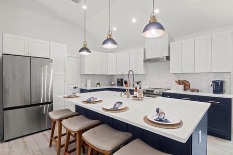 Stylish & Functional (FULLY STOCKED) Kitchen: Experience the perfect blend of modern aesthetics and functionality in this kitchen, featuring white and navy cabinetry, elegant lighting, and thoughtful decor.