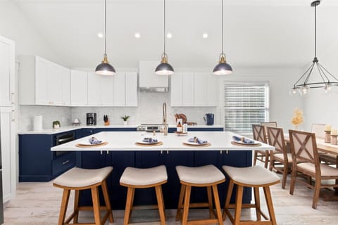 Bright, modern kitchen built for connection: With sleek navy cabinetry, elegant pendant lighting, and seating for 4 at island (and 8 at table), this open-concept kitchen is the heart of the home—perfect for cooking, gathering, and late-night laughs.