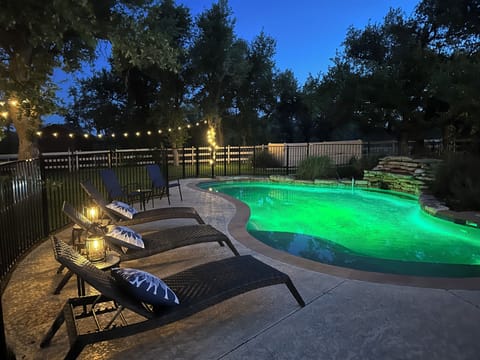 Enclosed pool and spa with waterfall at sunset