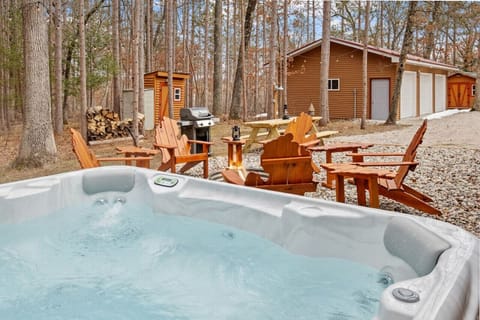 Relax in the hot tub and unwind under the trees. Enjoy a meal or evening conversations by the outdoor dining area, perfect for a cozy getaway.