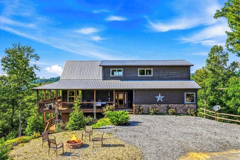 A charming mountain retreat with a distinctive star marking the entrance, set among lush greenery and featuring a spacious fire pit area for evening gatherings.