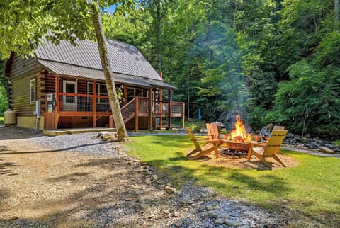 Charming riverside cabin nestled in lush forest with inviting fire pit and Adirondack chairs, offering peaceful natural surroundings for your mountain escape.