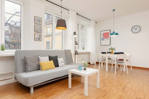 A bright living area with a gray sofa, a white coffee table, and large windows letting in plenty of natural light.

