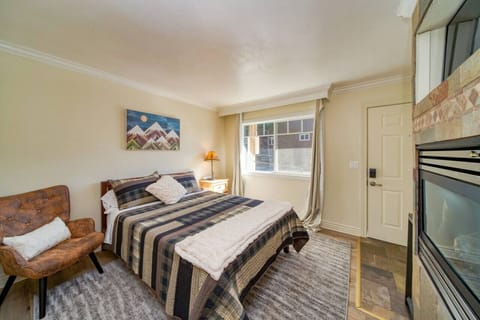 Main living space with a queen bed, sitting chair, gas fireplace , and smart TV with Netflix.