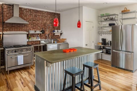 Cook up a delicious meal in this stylish industrial kitchen featuring exposed brick, stainless steel appliances, and a spacious island.