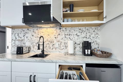 Kitchenette with storage and essential appliances like Keurig pod coffee, toaster, blender, microwave & small refrigerator.