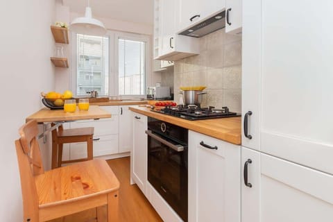 Compact kitchen with modern appliances, including a stove, oven, and cabinets in a light color scheme.