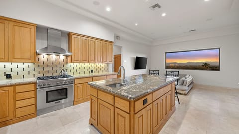 Modern kitchen with light wood cabinetry, granite countertops, and views.