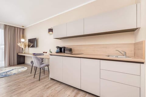 A modern kitchenette with minimalist cabinets, built-in appliances, and wooden countertops.