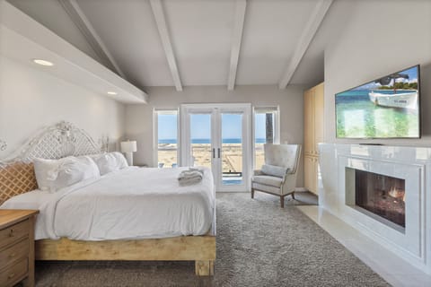 Primary bedroom features a king bed, ocean views, balcony access, a TV, a fireplace, and an ensuite bathroom.