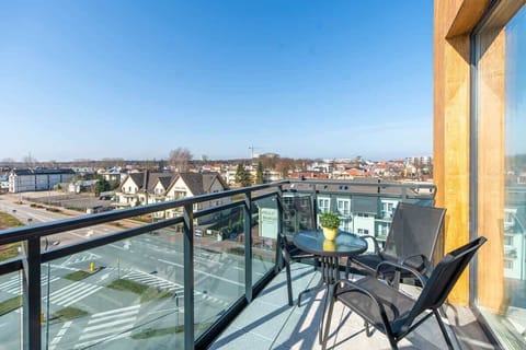 A balcony with a seating area, offering panoramic views of rooftops and the surrounding area.

