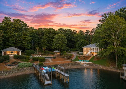 Twilight lakefront aerial with a private dock, pool area, and peaceful shoreline setting.
