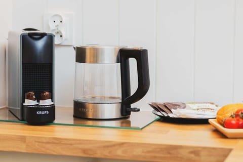A close-up of a wooden kitchen countertop with black electric kettle and coffee maker.
