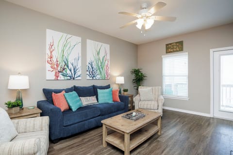 Sink into this cozy living room where coastal artwork and navy sofa create your perfect retreat space with ceiling fan comfort.