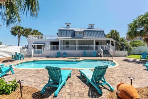 Sunlit pool area w/ loungers & palm trees, perfect for relaxing under blue skies.