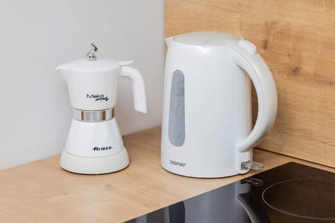A close-up of a white kettle and coffee maker on a wooden counter, emphasizing convenience.

