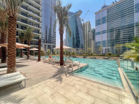 Dive into luxury in this sleek cityside pool surrounded by palm trees and towering skyscrapers. Perfect for sunbathing, swimming, and soaking up vibrant urban energy in style.