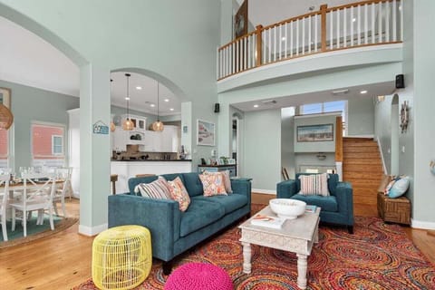 Open living room with balcony access, loft overlook, and abundant natural light.