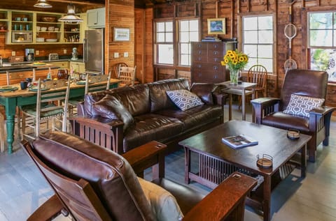 Living room with Stickley leather sofa set facing a wood fire cast iron stove and with over a dozen large windows on three sides offering glorious views of the lake