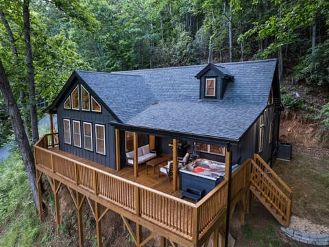 Charming cabin with a wooden deck and a hot tub nestled in the woods.