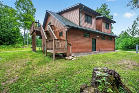 The Taj Woodside is the upper story of a  two-story brown wood cabin with a large deck and a staircase leading to an upper entrance.