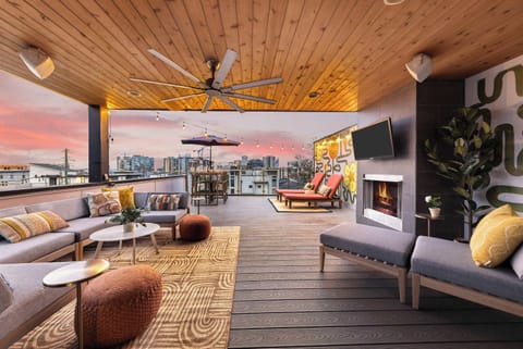 This expansive rooftop veranda is the ultimate entertaining space, featuring a large sectional sofa, a sleek outdoor fireplace, and a smart television mounted on the wall. Perfect for relaxing and hosting guests. 