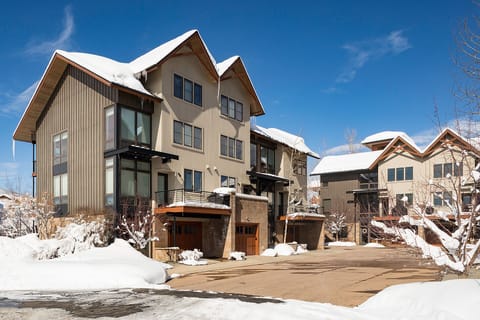 Modern alpine townhomes framed by fresh snow and bright blue skies in a scenic mountain neighborhood.