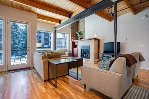 Unwind by your crackling fireplace in this bright living room with exposed wood beams and mountain views.