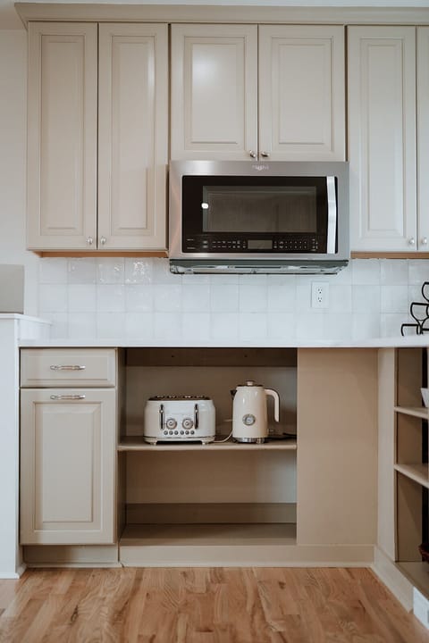 - Easy access to a modern microwave, stylish toaster, and matching electric kettle
- Creamy cabinetry with smooth pulls for a seamless cooking experience
- Glossy tiled backsplash reflects warm lighting and a clean aesthetic
