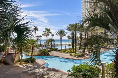 Relax by the resort-style pool with ocean views framed by palm trees.