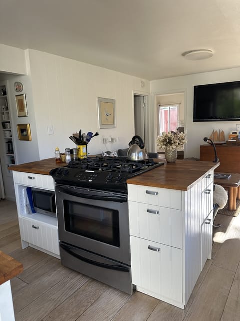 Butcher block island has 4 burner propane gas stove, microwave, and storage.