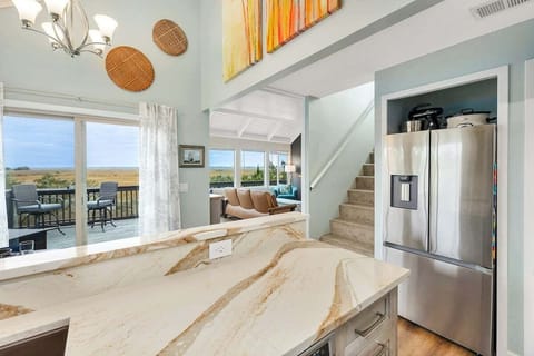 Open kitchen with marble island, stainless refrigerator, and marsh views