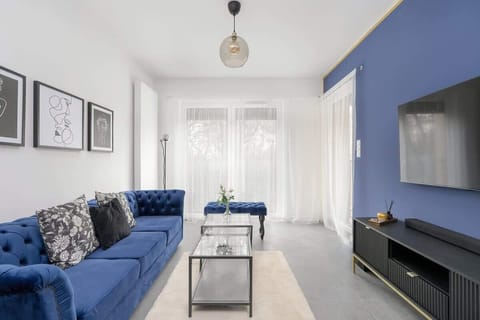 A modern living room with a vibrant blue accent wall, comfortable sofa, and minimalist decor, creating a stylish and cozy atmosphere.
