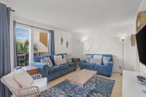 Sink into plush blue sofas in your bright living room, where coastal accents and a textured accent wall set the tone for relaxation after sunny beach days.