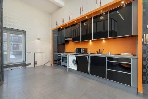 A modern kitchen with black and orange cabinets, sleek countertops, and a spacious layout.