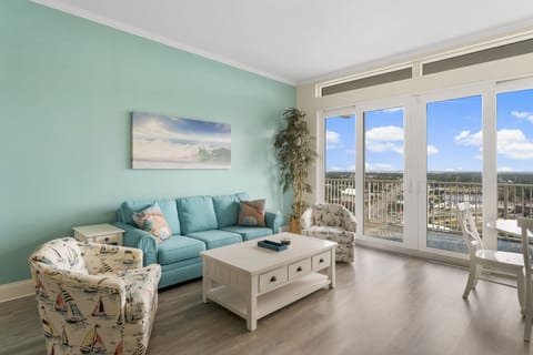 Relax in this bright living room with coastal-inspired decor and large windows offering city views.