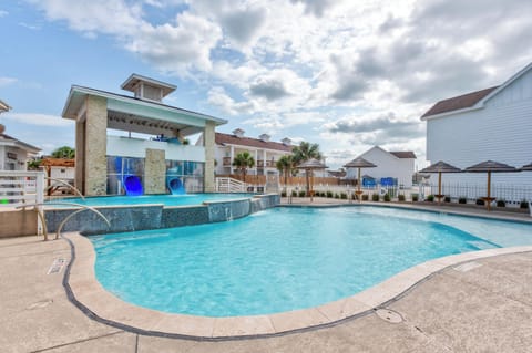 Resort-style pool area with children's splash features and covered pavilion surrounded by residential buildings.