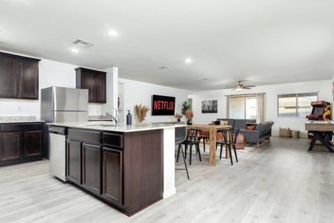 Prepare meals in the kitchen while interacting with friends and family in the living room.