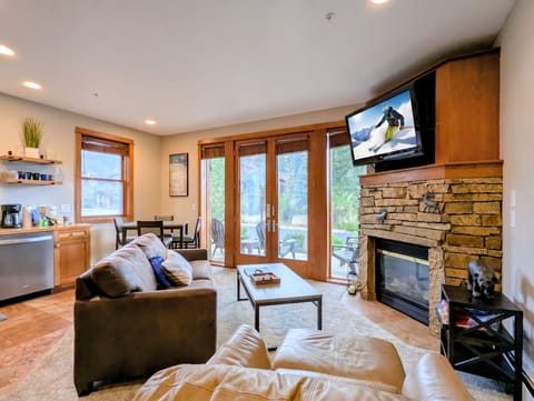 Relax in your inviting living room, where plush seating faces a warm stone fireplace. French doors frame mountain views, filling the space with natural light and alpine beauty.