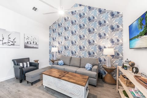 Sink into your stylish queen size sleeper sofa surrounded by tropical palm wallpaper and coastal artwork, where comfort meets beach-inspired elegance.