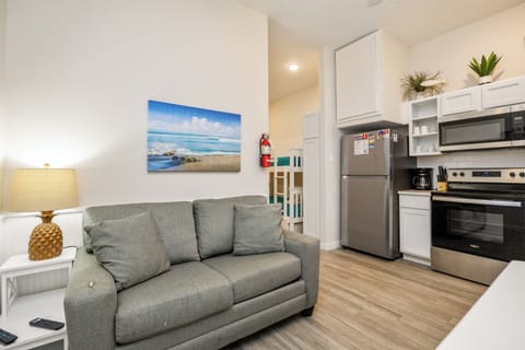 Unwind in your stylish open-concept space with a plush sofa and fully equipped kitchen featuring modern appliances and coastal-inspired decor.