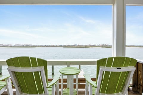 Relax in colorful Adirondack chairs on your private balcony, watching boats drift by on calm waters while distant homes dot the horizon.