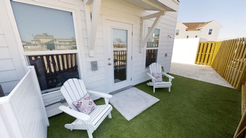 Your private outdoor sanctuary awaits with comfortable Adirondack chairs on artificial turf, perfect for morning coffee or evening relaxation.