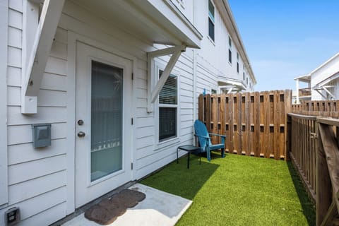 Your private backyard retreat features synthetic grass and a cozy turquoise chair—perfect for morning coffee or evening relaxation in your own outdoor oasis.