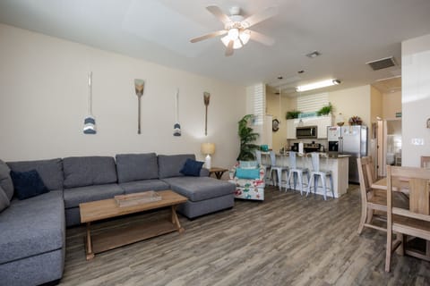 Relax on your spacious sectional sofa in this open-concept living area, where coastal decor meets modern comfort with a fully equipped kitchen nearby.