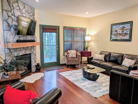 Bright living room with a gas fireplace, Smart TV, and peaceful forest views