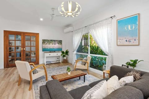 Relax in the light-filled main living area, where coastal styling, garden views, and comfortable seating create an inviting space to unwind after the beach.