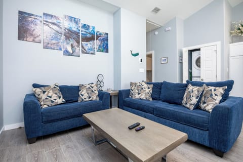 Sink into plush navy sofas with geometric pillows in your bright living space, where ocean-inspired art creates a calming retreat.