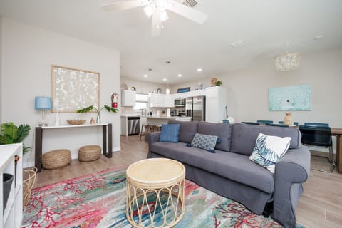 Relax in your bright open living space featuring a comfy sectional sofa, stylish decor, and fully equipped kitchen ready for your vacation.
