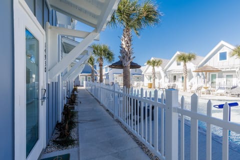 Coastal resort featuring white beach cottages with palm trees and swimming pool under sunny blue skies.